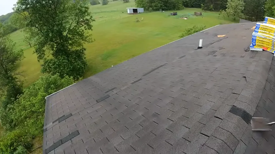 Partially stripped asphalt shingle roof with new shingle bundles staged