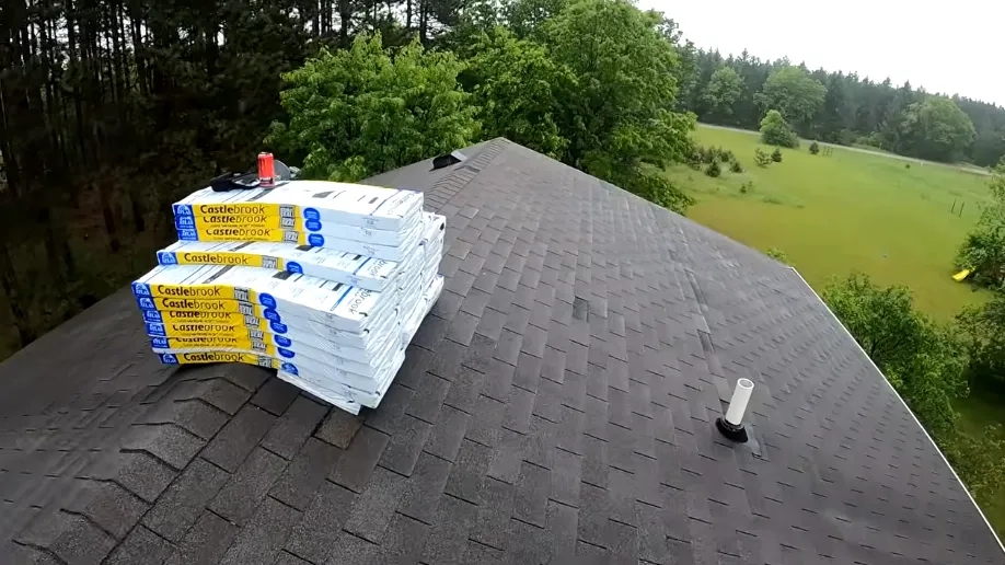 Stack of new shingle bundles staged on a roof ridge for a roof replacement