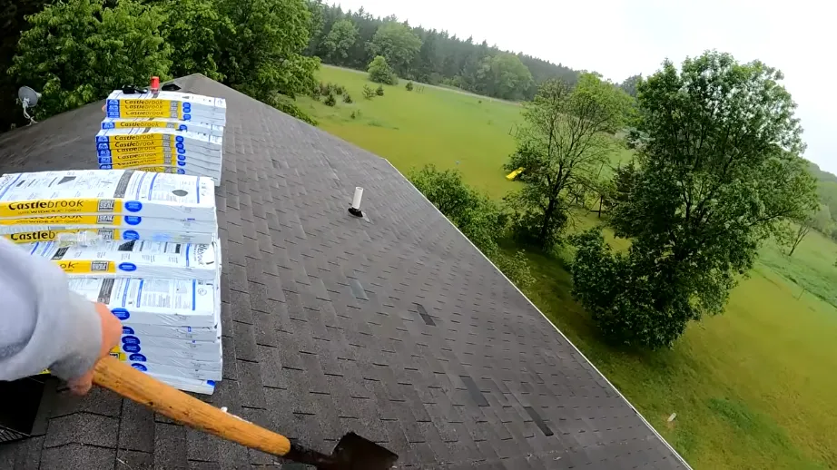 Tear-off shovel and new shingle bundles on a roof during replacement