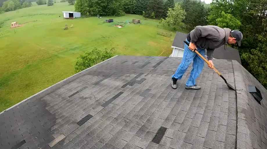 Roofer stripping old asphalt shingles down to the underlayment